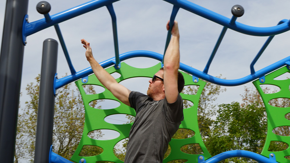 man with sunglasses playing on monkey bars